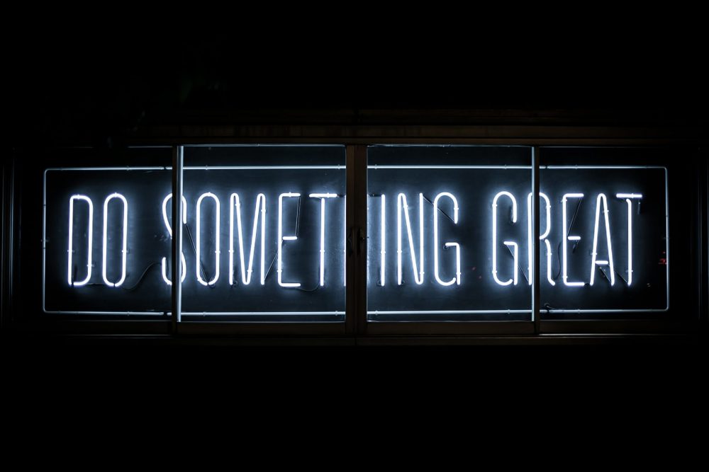 Sfondo nero e una scritta fatta con luci al neon che dice: do something great, tradotto: fai qualcosa di grande.